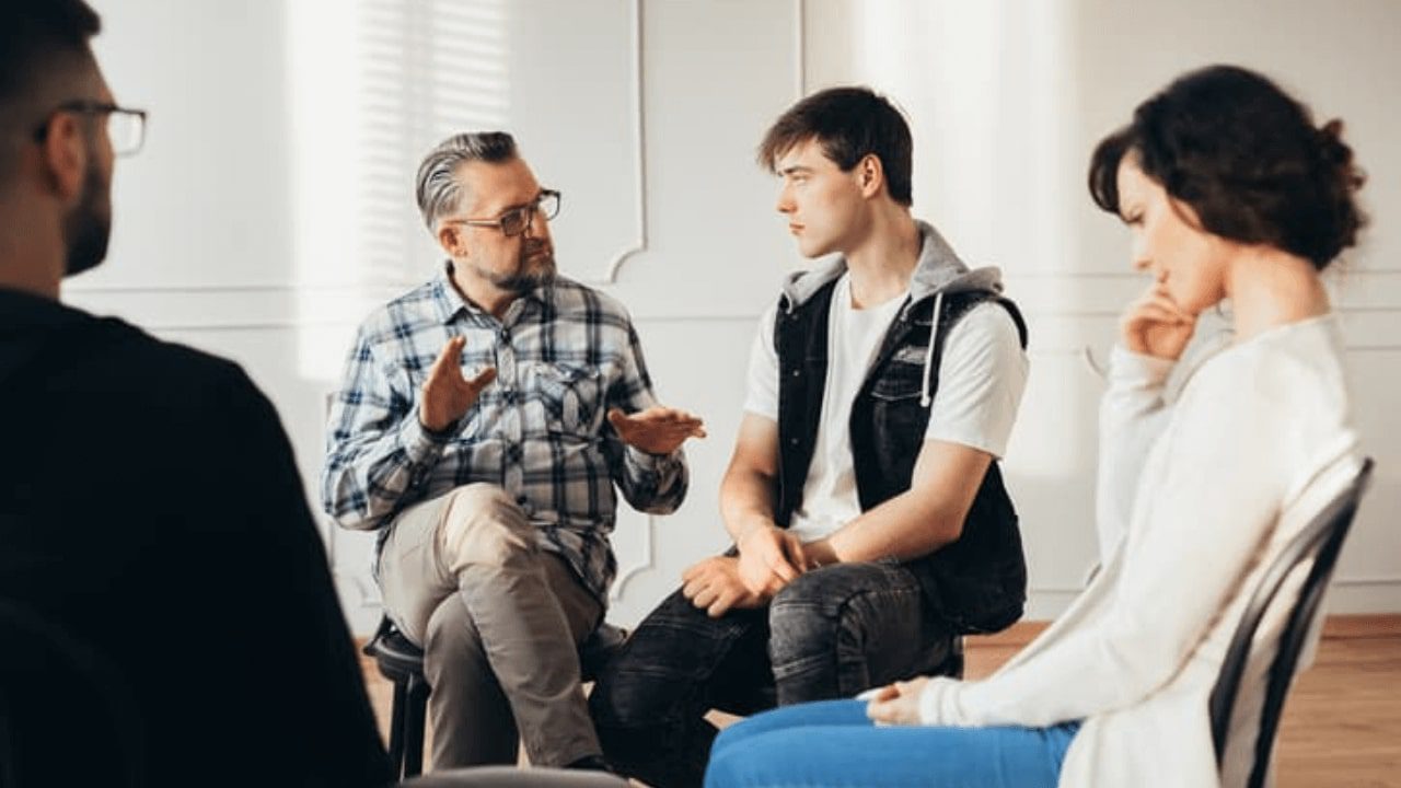 a group of people sitting around a table talking to each other