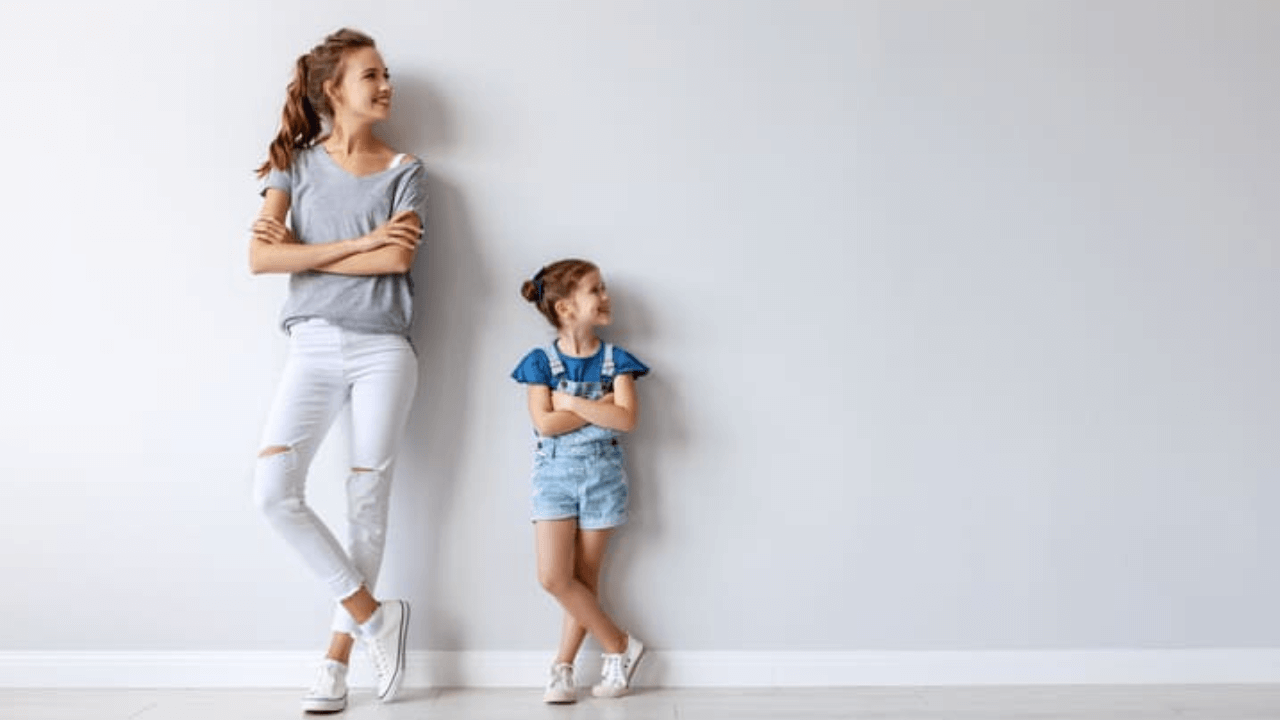 a woman and a child standing next to each other in front of a wall