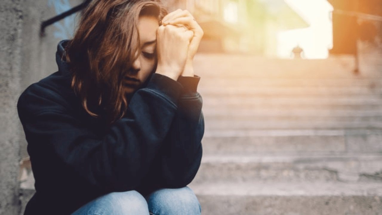 arafed woman sitting on steps with her head in her hands