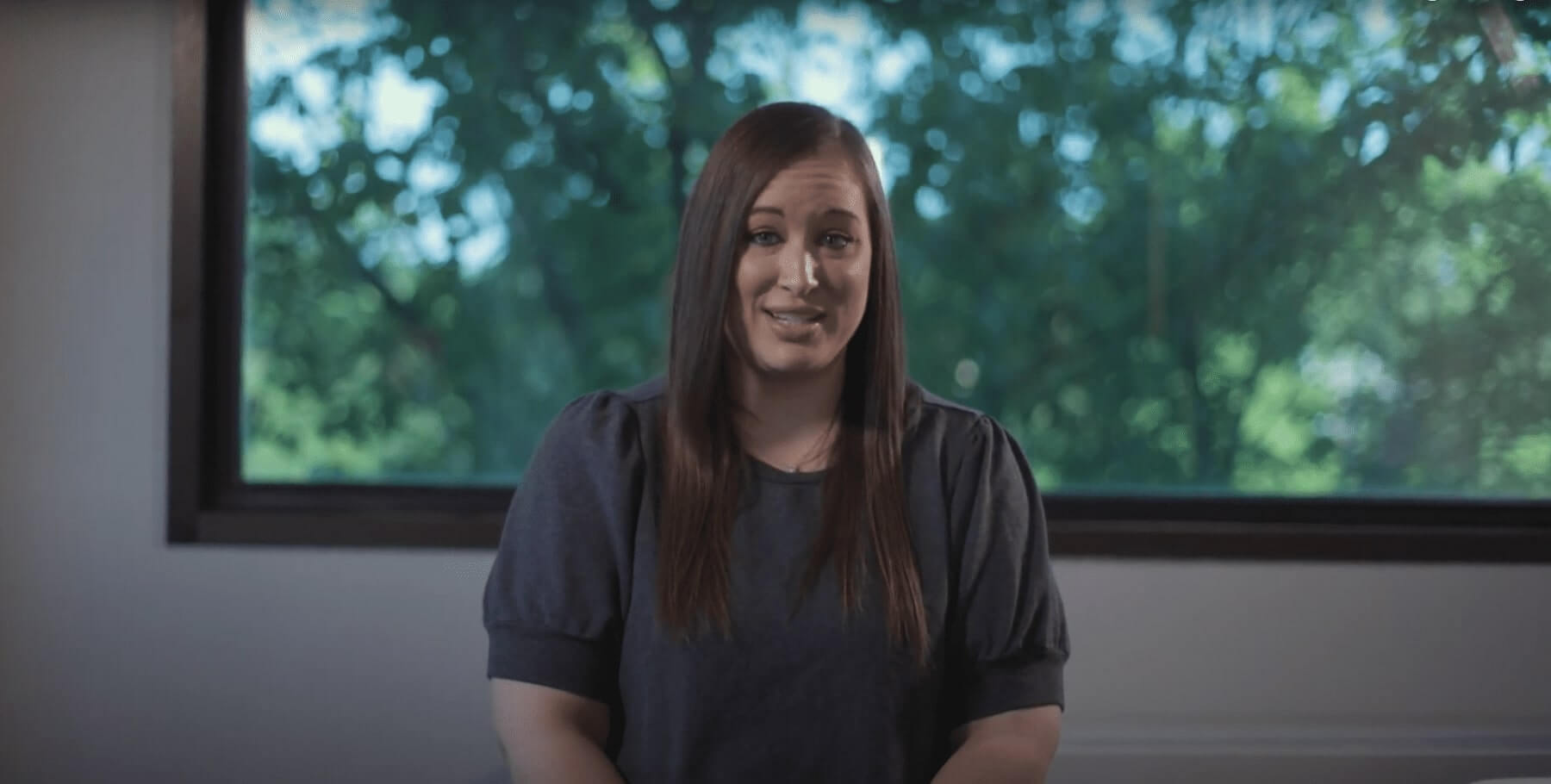 there is a woman sitting in front of a window with a smile on her face