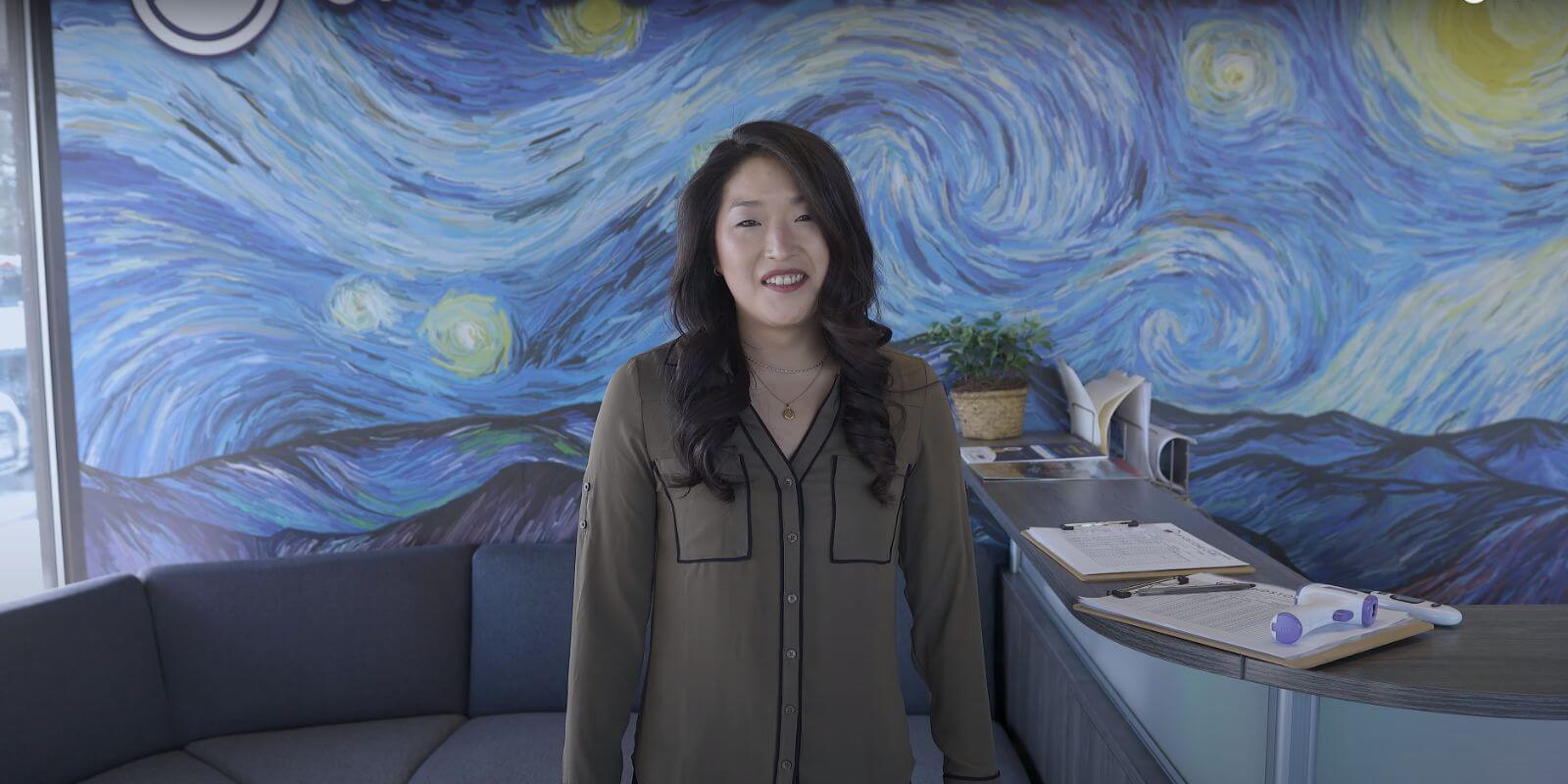 there is a woman standing in front of a painting in the lobby of the Colorado Springs outpatient center.