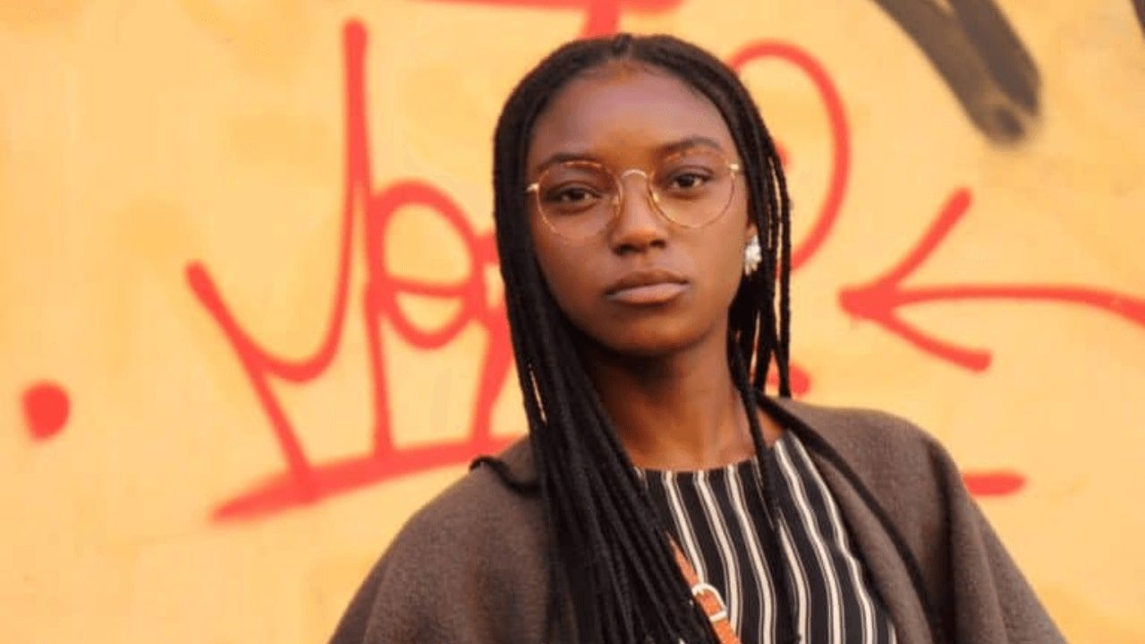 arafed woman with glasses standing in front of a graffiti wall