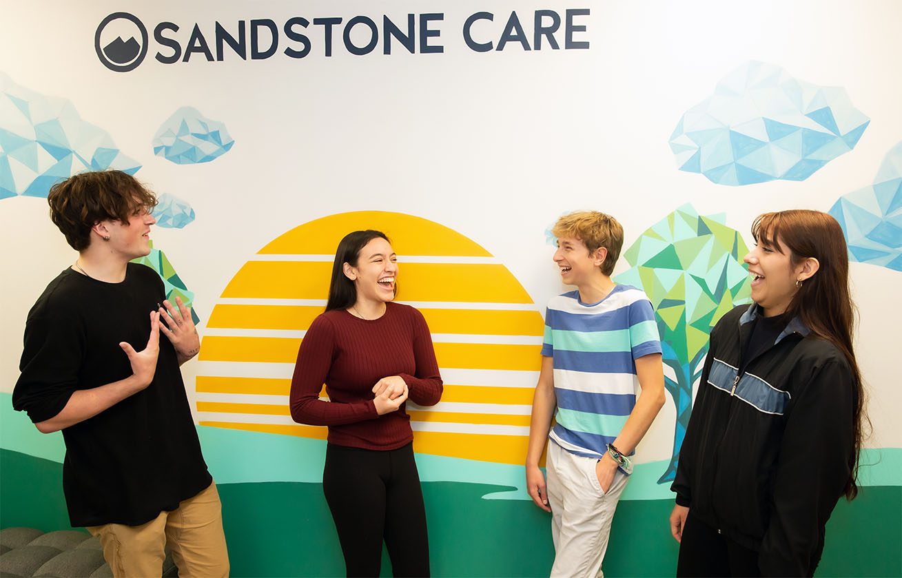 A group of people standing in front of a wall with a sign that says sandstone