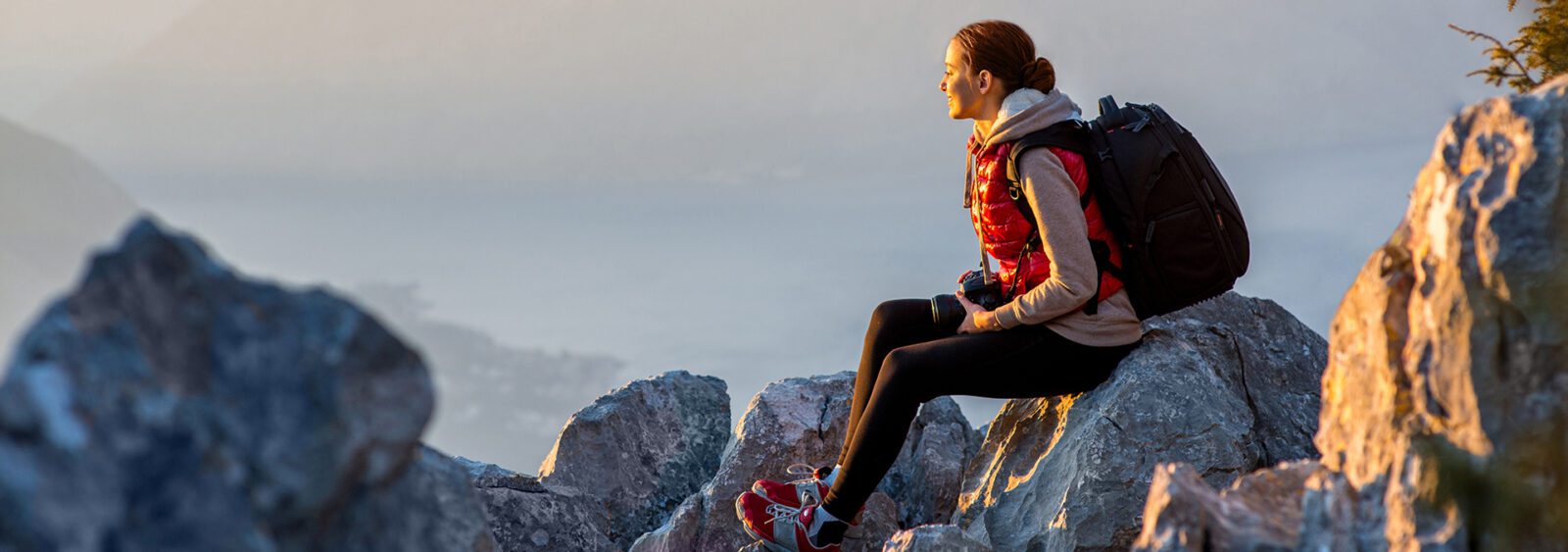 there is a woman sitting on a rock with a backpack