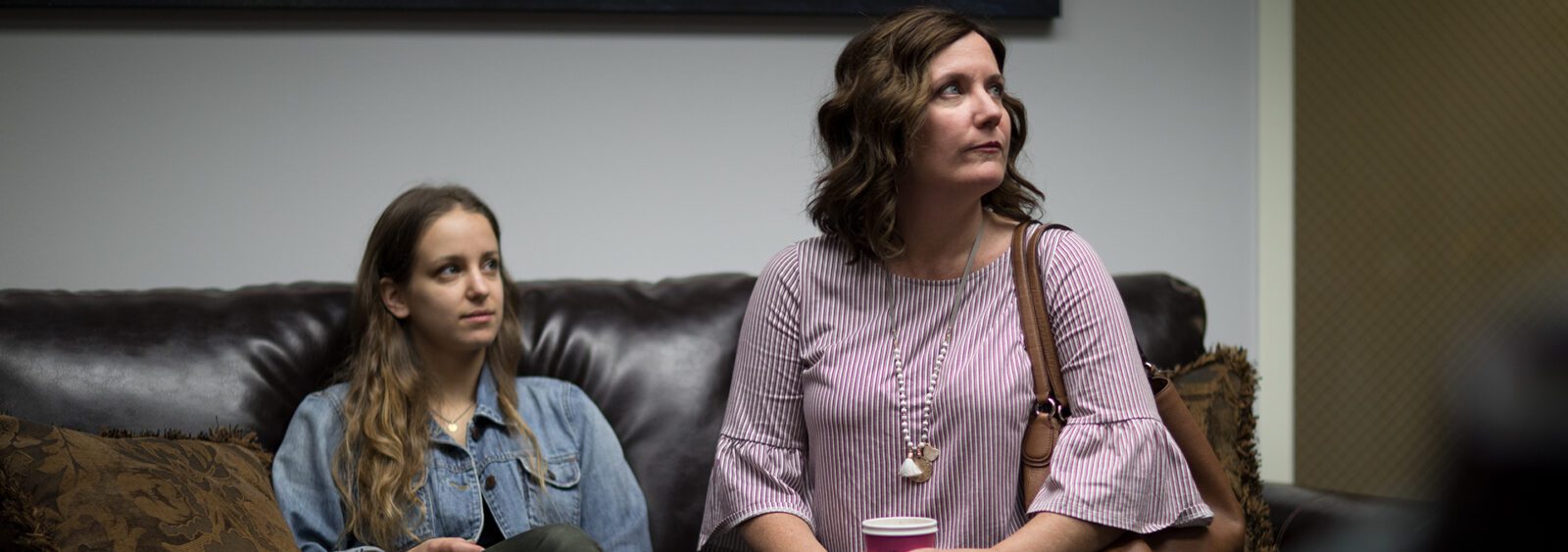 they are two women sitting on a couch talking and drinking