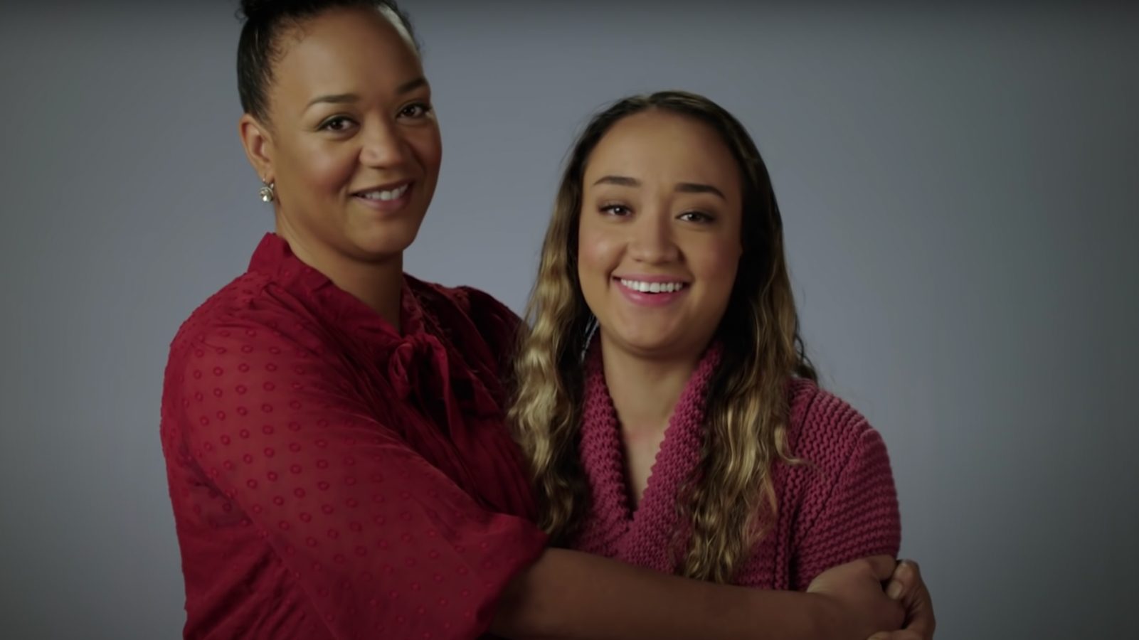 A parent hugging her teen, smiling