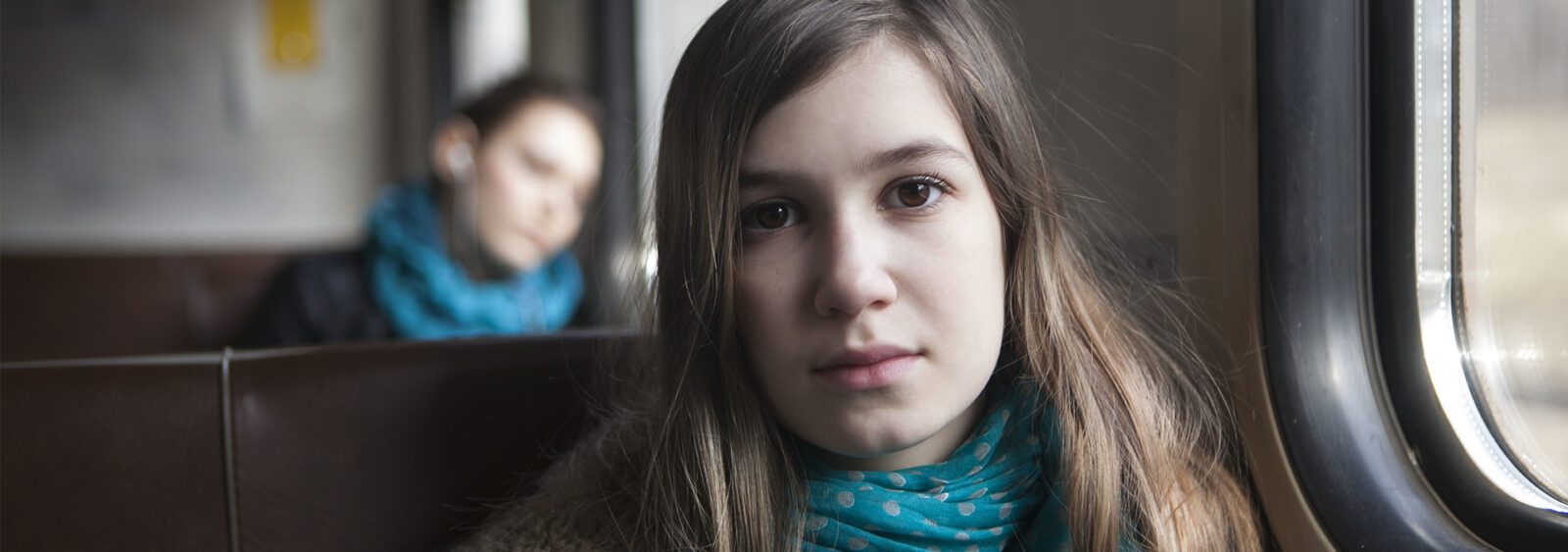 there is a woman sitting on a train looking out the window