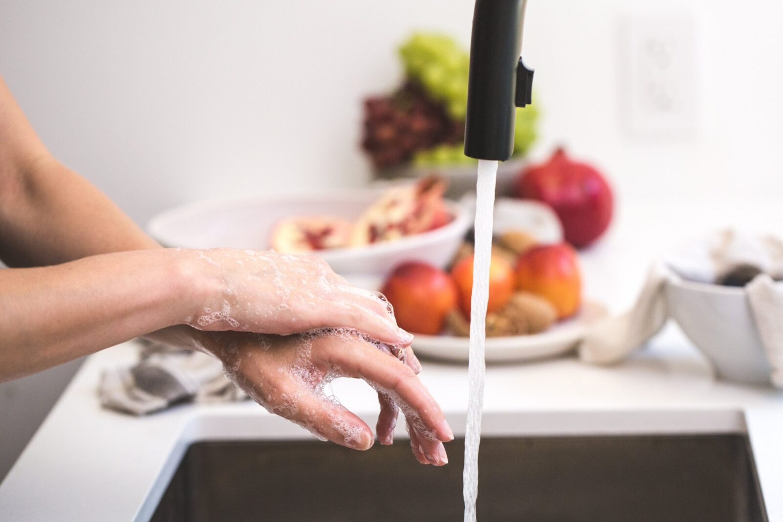 someone washing their hands in a kitchen sink with soap