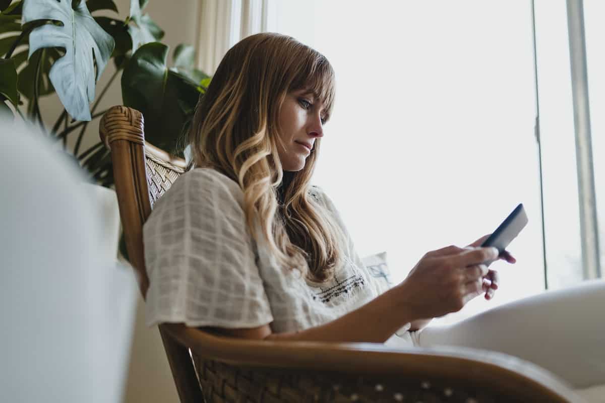 woman sitting in a chair looking at her cell phone