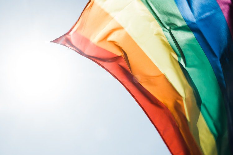 a close up of a rainbow flag flying in the sky