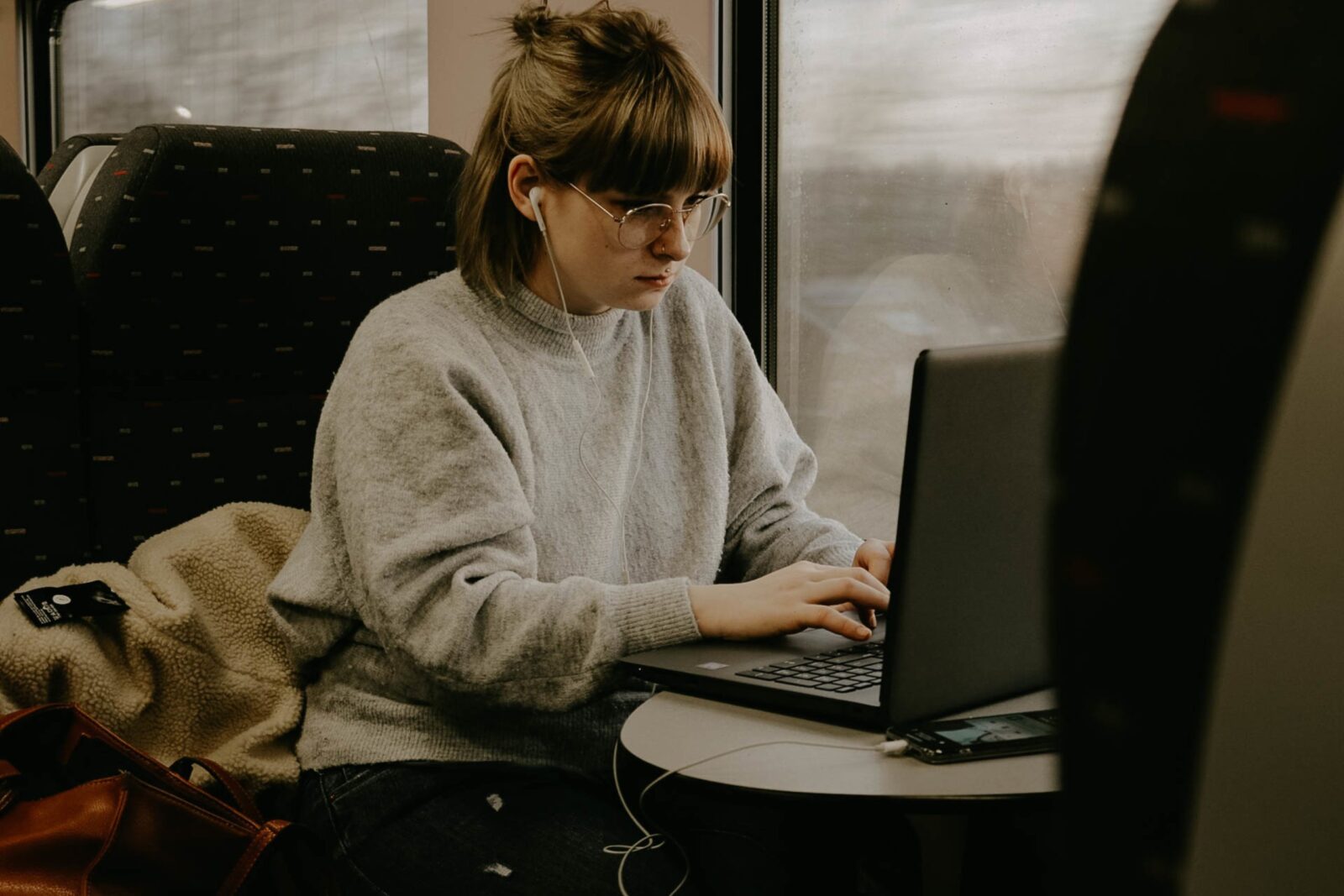 woman sitting on a train using a laptop computer