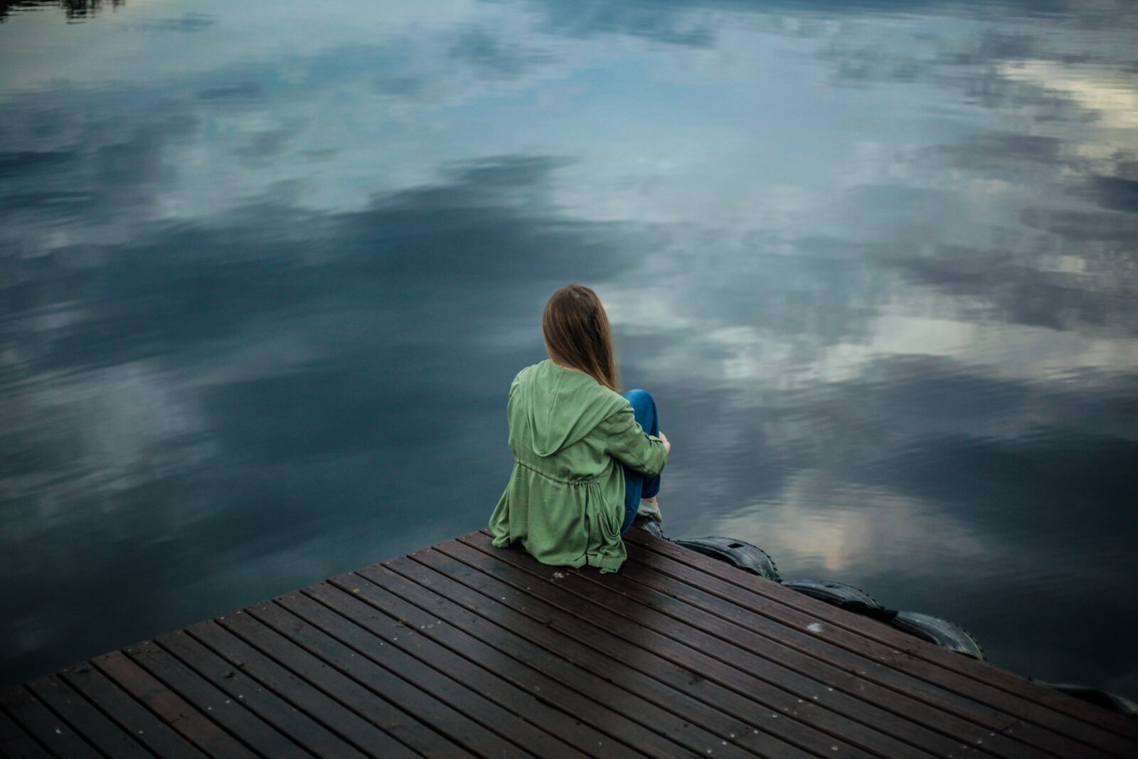 there is a woman sitting on a dock looking at the water