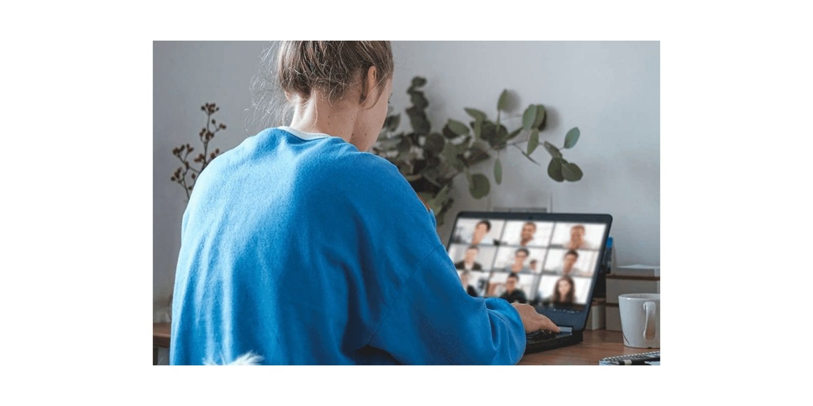 a woman sitting at a desk with a laptop computer and a plant