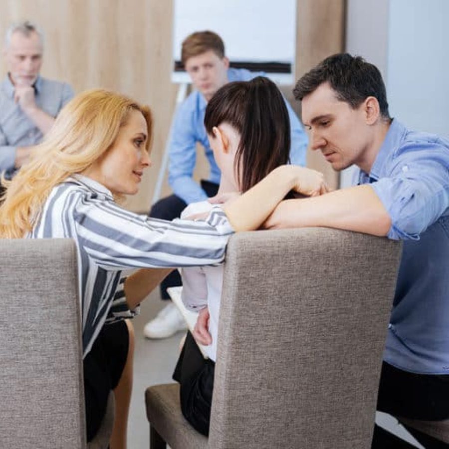 arafed group of people sitting in a meeting room with one woman covering her face