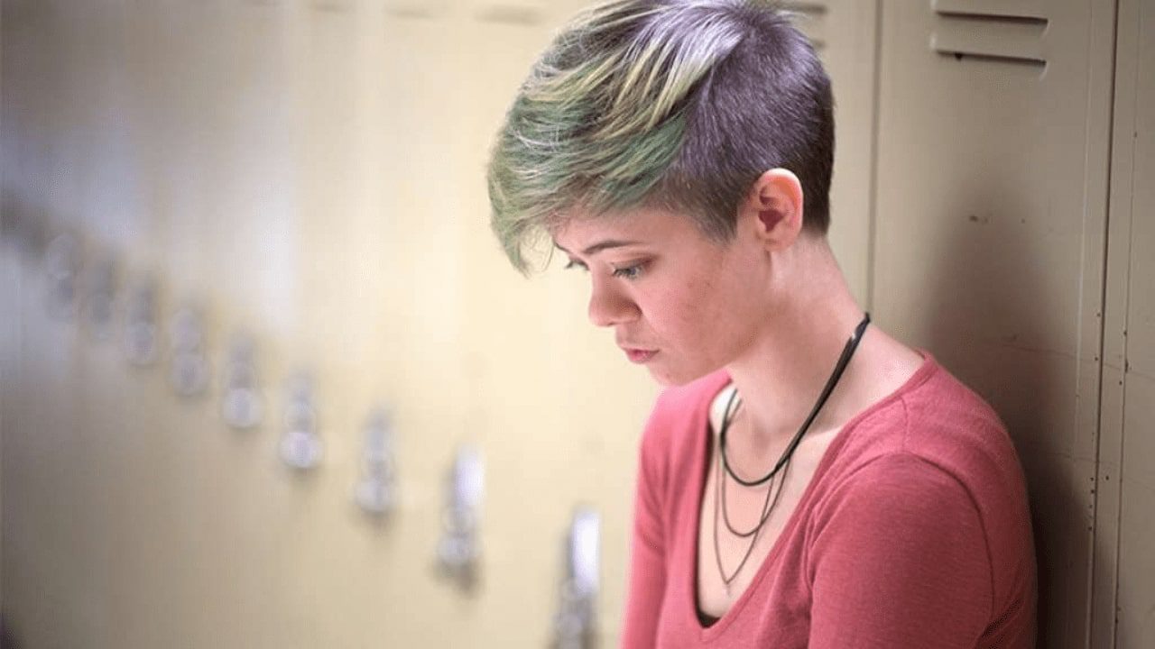 arafed woman with green hair and a necklace looking at her cell phone