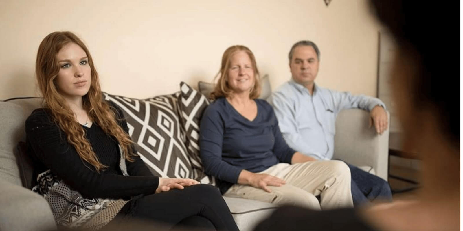 there are three people sitting on a couch in a living room