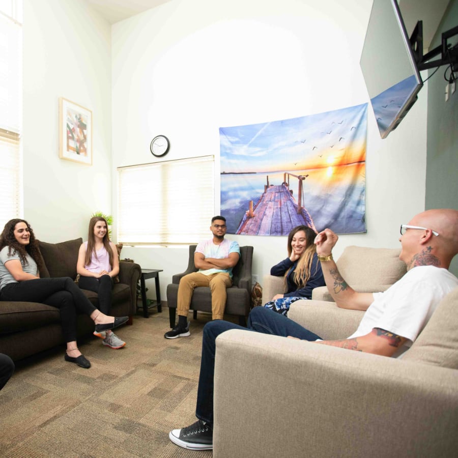 several people sitting in a room with couches and a television