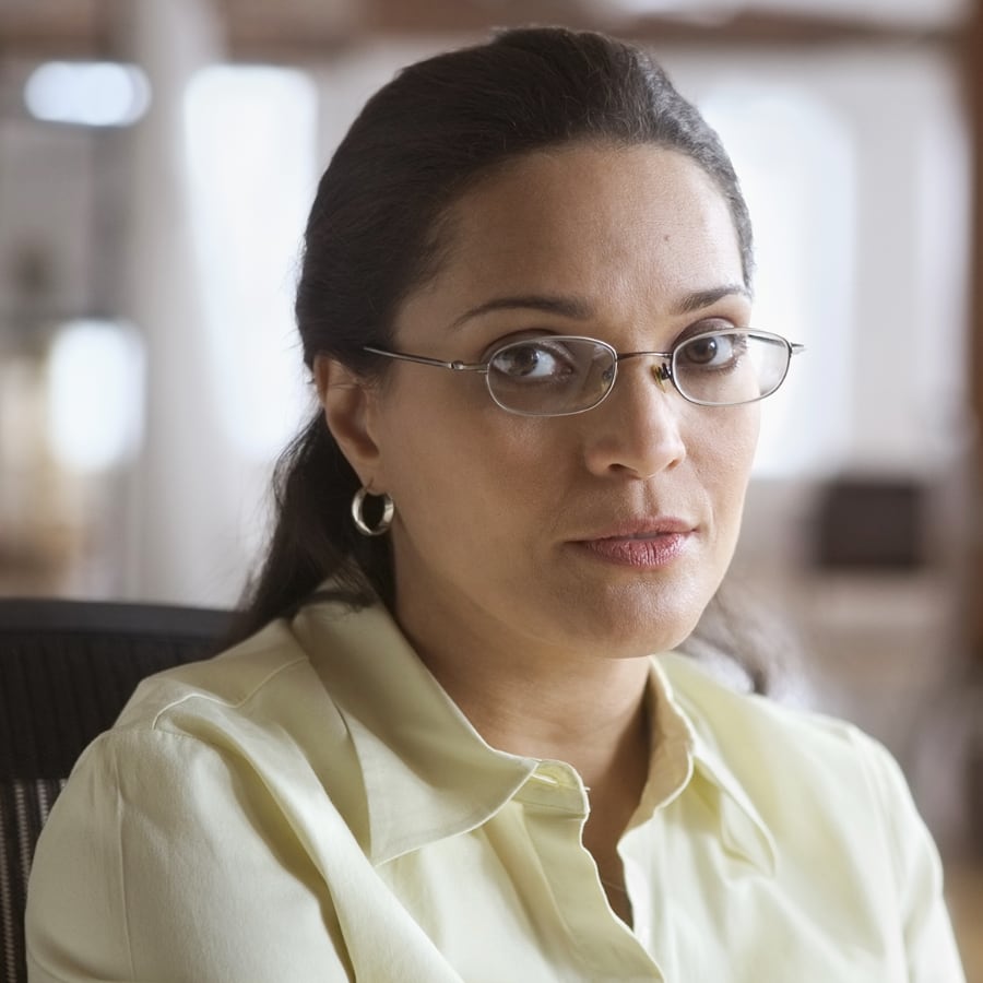 woman with glasses sitting in chair looking at cell phone