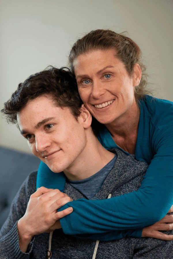 there is a woman hugging a man who is sitting on a couch