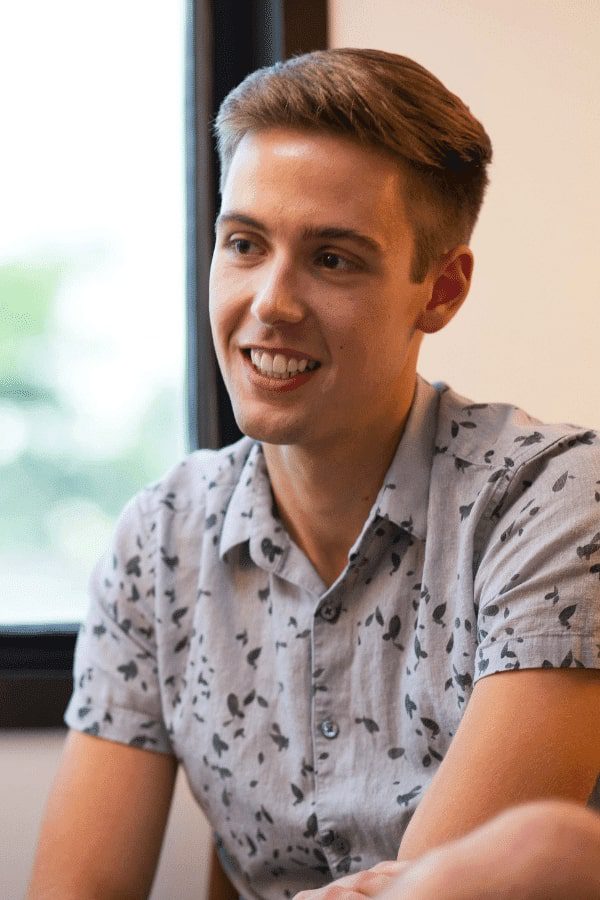 there is a man sitting in front of a window smiling