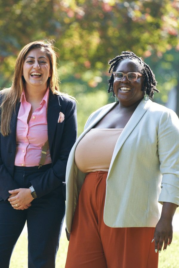 two women standing in a park smiling and laughing