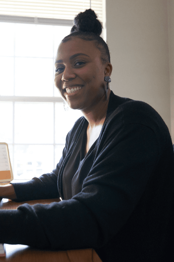 smiling woman sitting at a desk with a laptop computer
