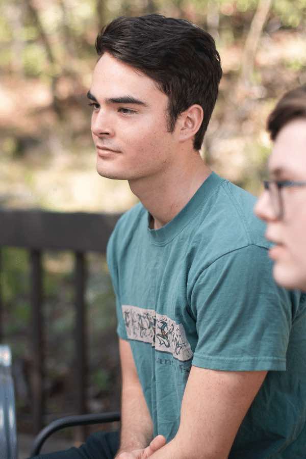 there are two people sitting on a bench outside talking