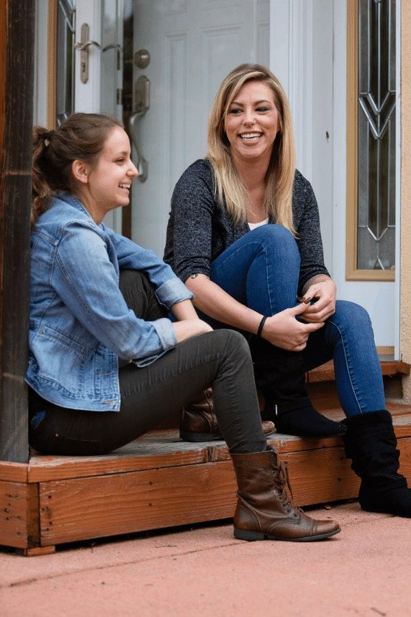 two women sitting on a step talking to each other