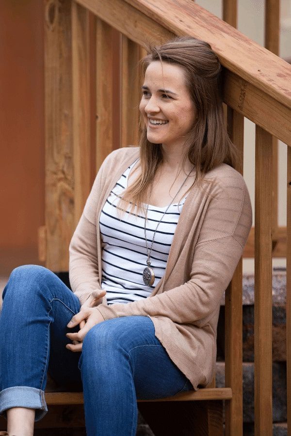 arafed woman sitting on a wooden bench smiling and looking at the camera