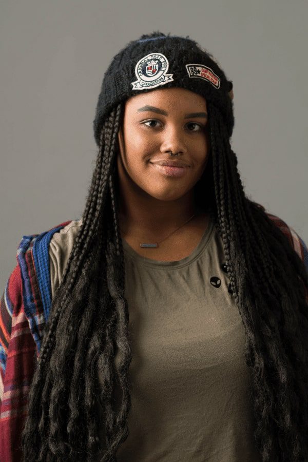 arafed woman with long hair wearing a hat and a plaid shirt