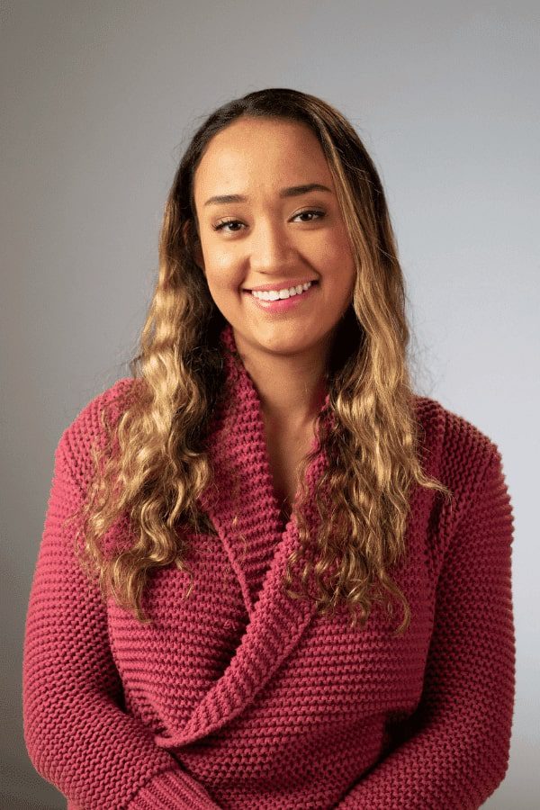 a close up of a woman in a pink sweater smiling