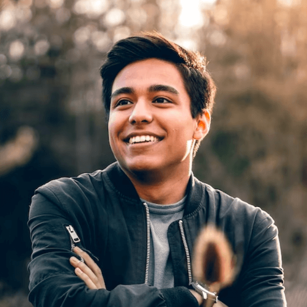 smiling man in black jacket with arms crossed and a dog in the background