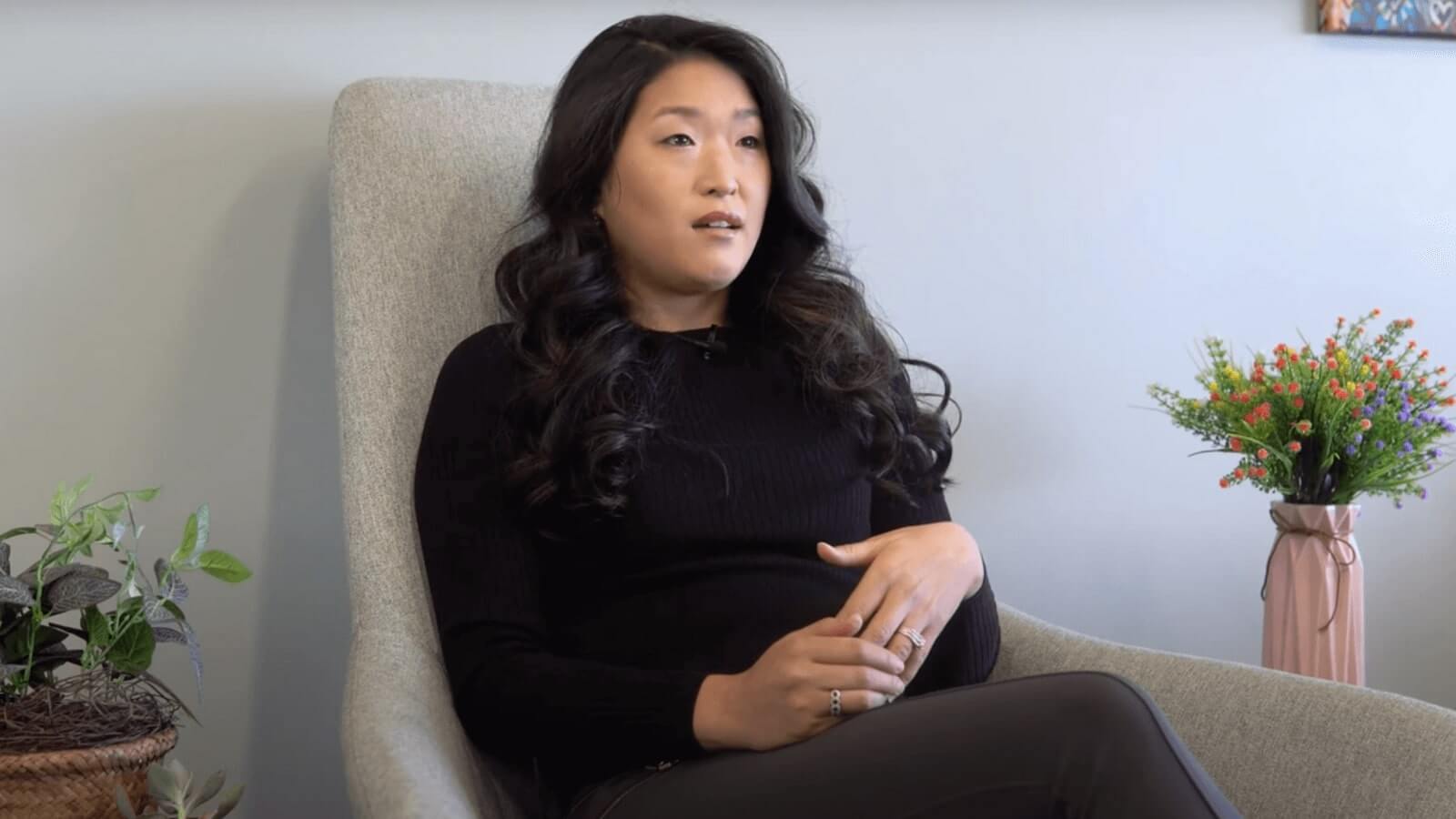 pregnant woman sitting in a chair with a flower pot in the background