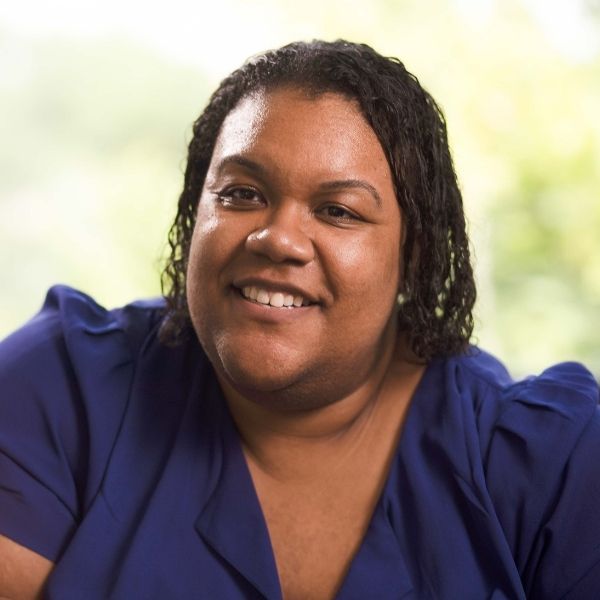 smiling woman with a blue shirt and a cell phone in her hand