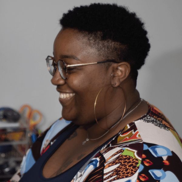 smiling woman with glasses and a colorful shirt holding a cell phone