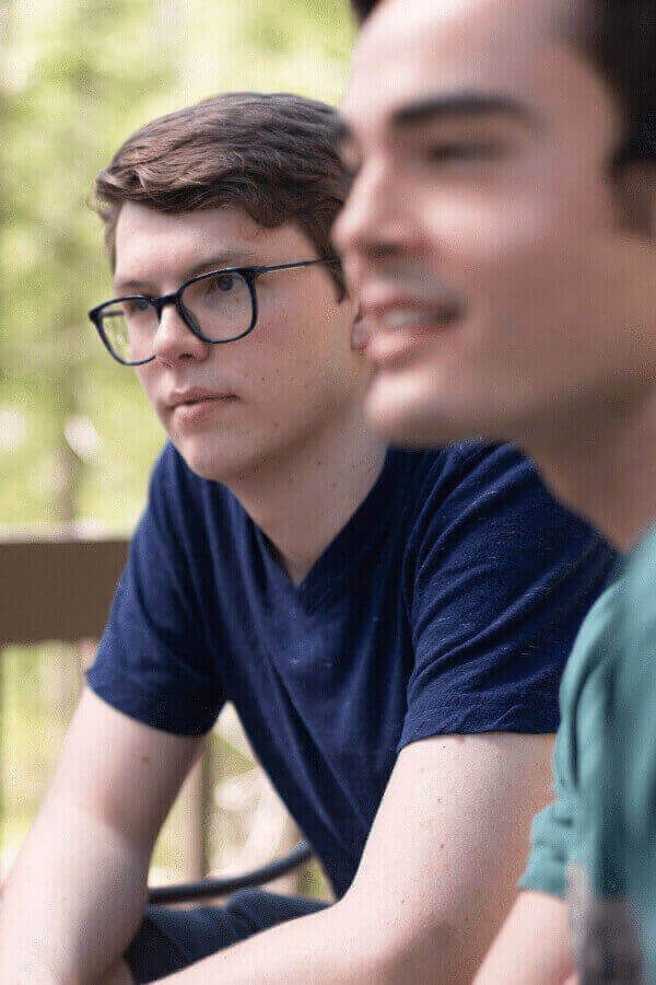 there are two men sitting on a bench with a remote control