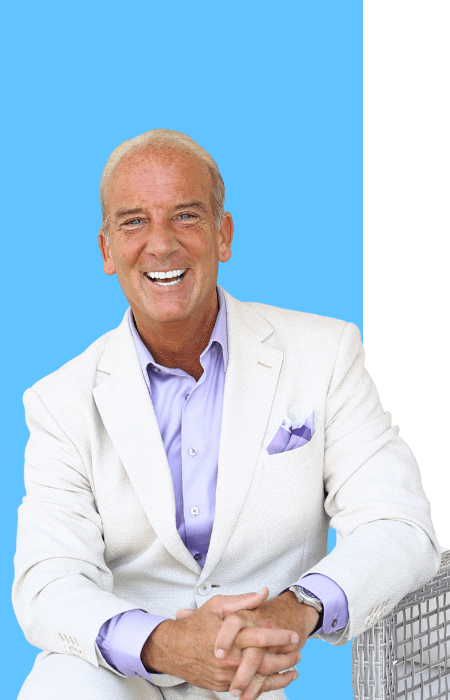 smiling man in white suit sitting on a chair with a blue background