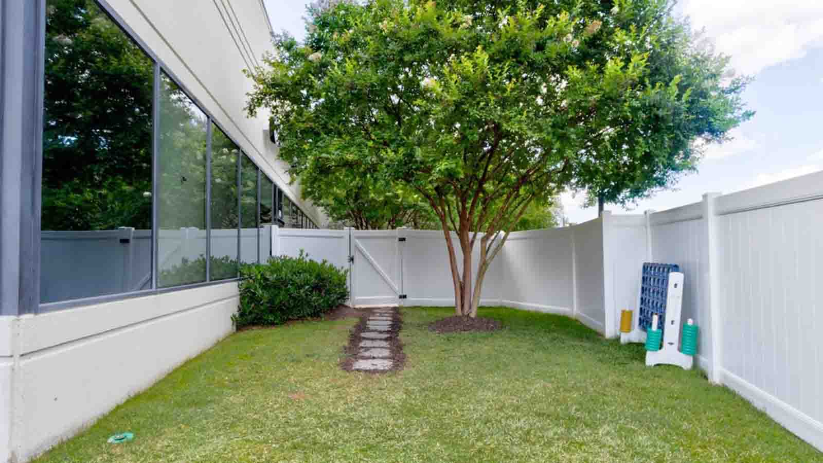 there is a small tree in the yard next to a white fence