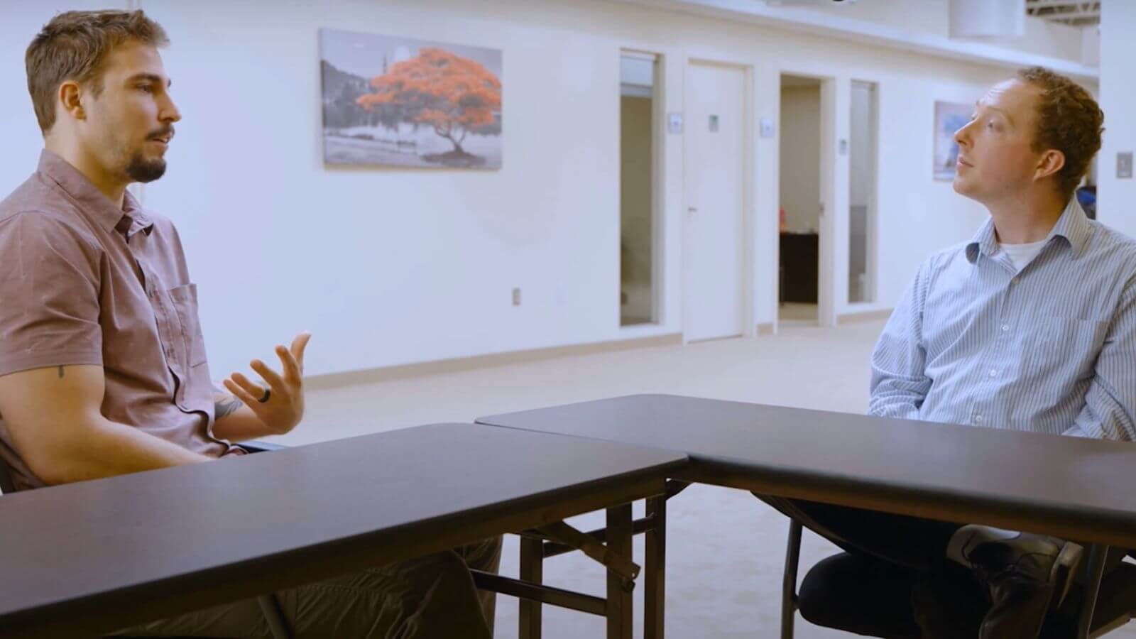 there are two men sitting at a table talking to each other