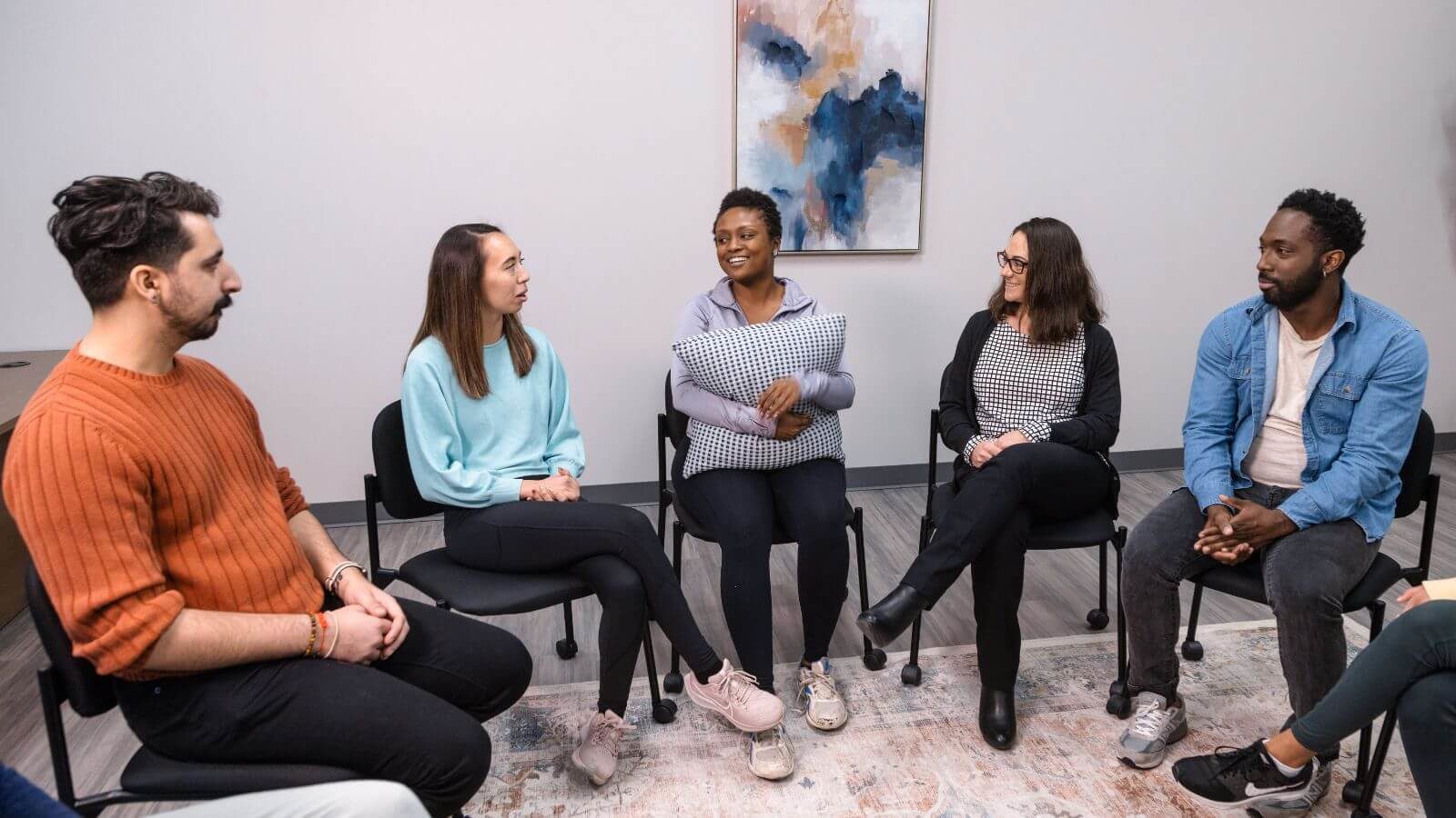 several people sitting in a circle talking to each other