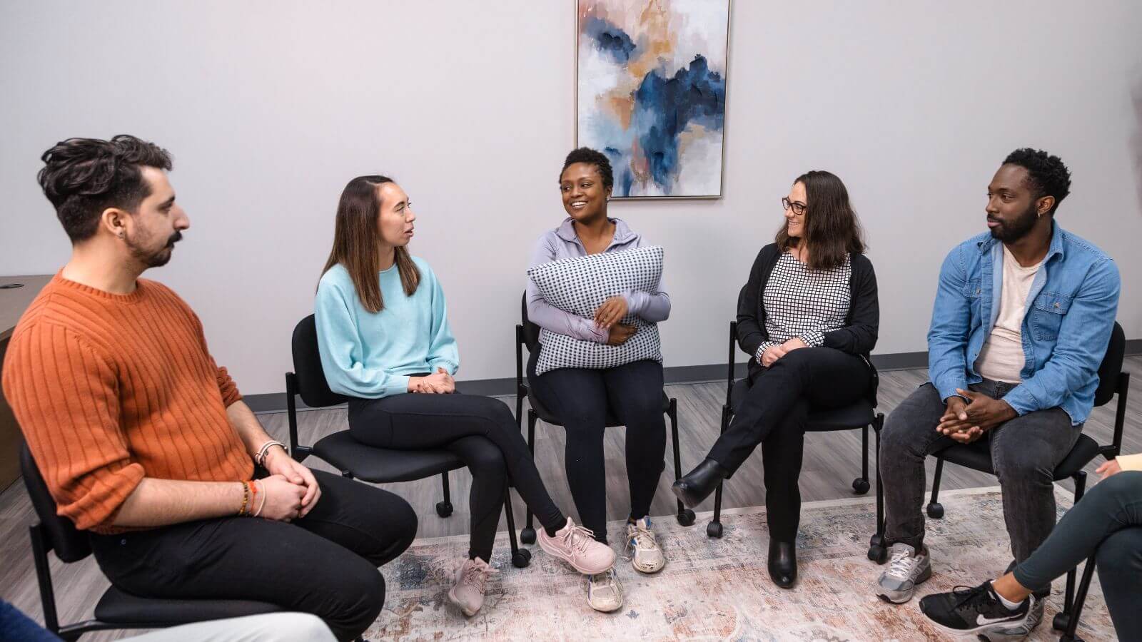 several people sitting in a circle talking to each other