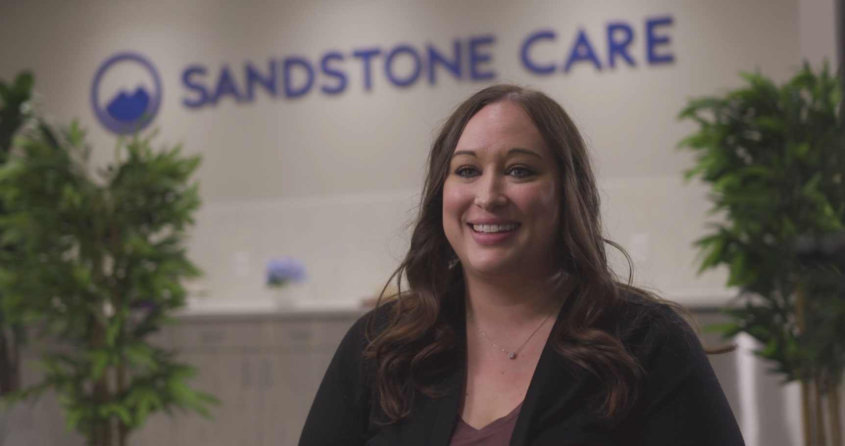 arafed woman standing in front of a sign that says sandstone care