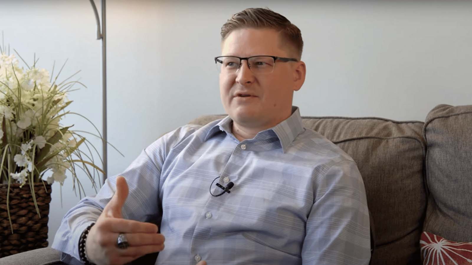 there is a man sitting on a couch with a flower in the background