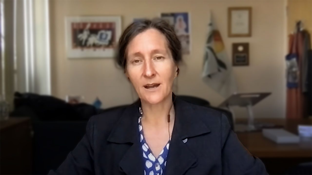 woman in a blue shirt and black jacket sitting at a table