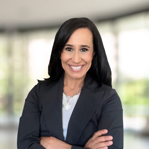 smiling woman in a black jacket and white shirt with arms crossed