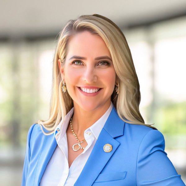 arafed woman in a blue jacket and white shirt smiling