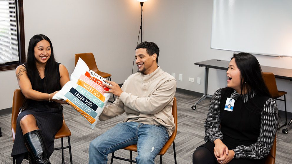Three smiling patients sitting next to each other in group therapy.