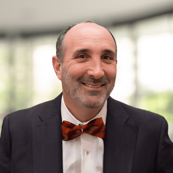 smiling man in a suit and bow tie in a room