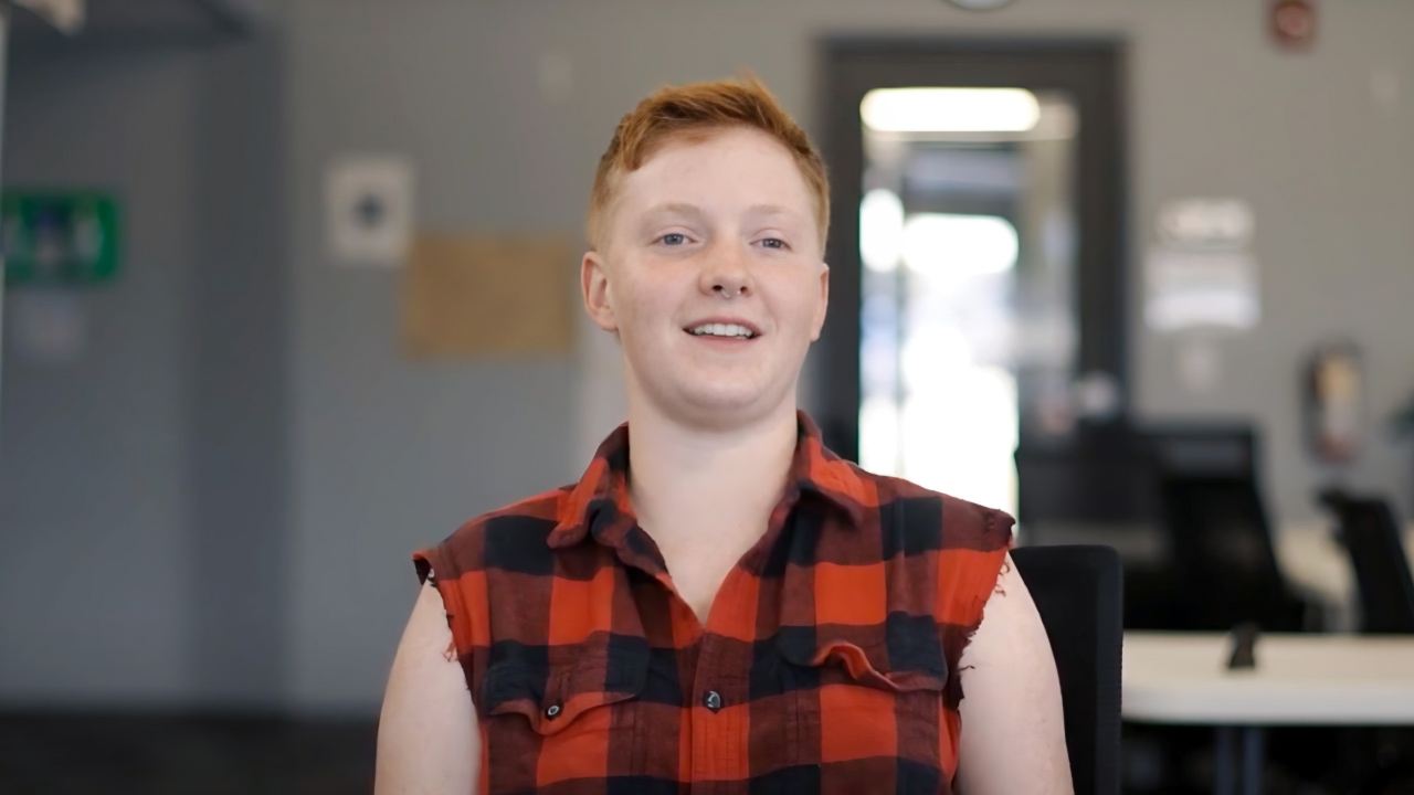 Red-headed teenager smiles at the camera.