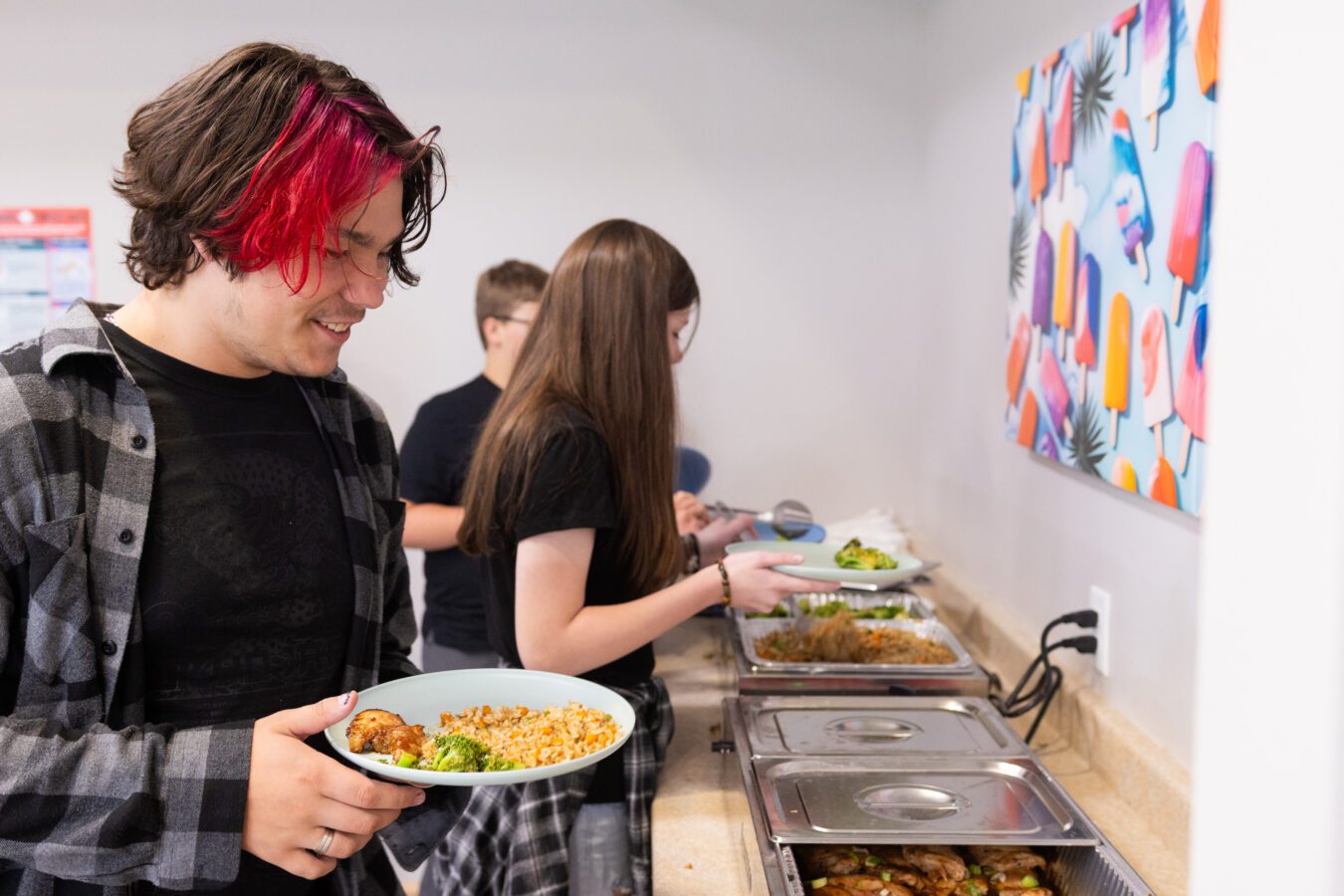 Teen boys and girls serving themselves lunch at a counter